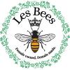 In the center of the Les Bees logo is a bee with a crown and the Les Bees name above its head and the phrase "Female owned. Female made." below the bee. All of this is inside a green circular border of leaves and flowers.